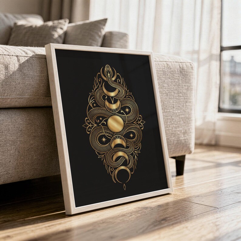 Gold snake moon phase wall art print in a white frame leaning against a gray sofa on a sunlit wooden floor.