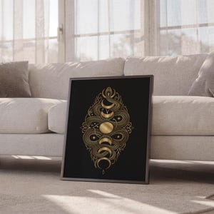 Gold snake moon phase wall art print leaning against a white sofa in a bright living room with sheer curtains.