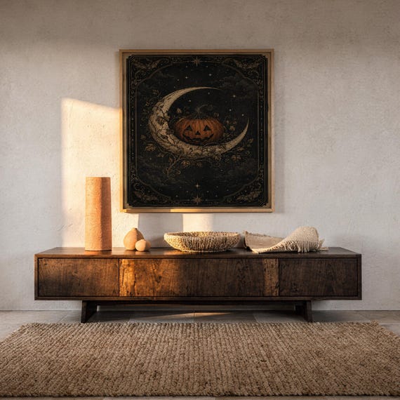 Vintage halloween moon wall art print hanging above a dark wood console and jute rug in a warm neutral interior.