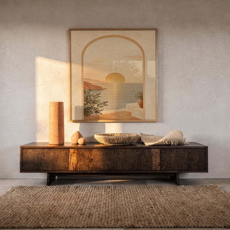 Mediterranean sunset arch print hanging above a dark wood console and jute rug in a warm neutral interior.