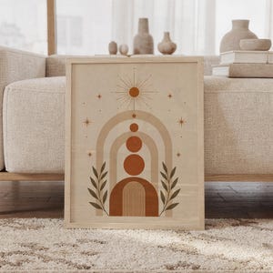 Framed boho geometric arch wall art print leaning against beige sofa in living room with terracotta circles.