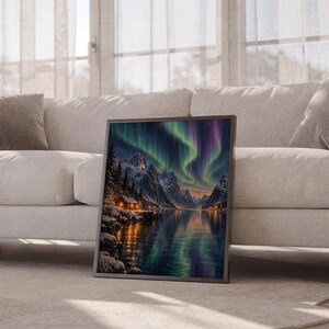 Aurora borealis mountain landscape wall art print leaning against a white sofa in a bright living room with sheer curtains.