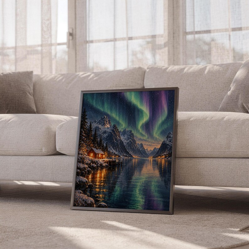 Aurora borealis mountain landscape wall art print leaning against a white sofa in a bright living room with sheer curtains.