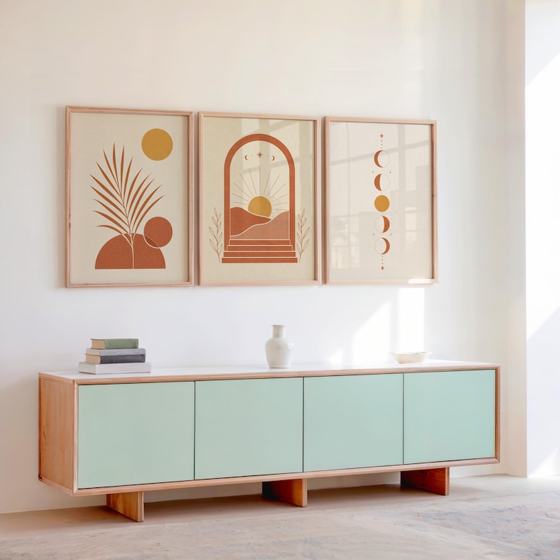 Set of 3 gallery wall art prints featuring mid century terracotta designs hung above a sleek contemporary mint green console sideboard cabinet in a modern home interior setup with high ceilings.
