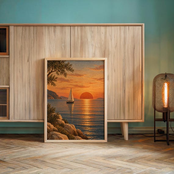 Sunset sailboat wall art print leaning against a wooden cabinet by a teal wall beside a glowing floor lamp.