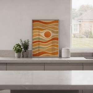 Abstract wavy sun print standing on a white kitchen counter beside potted herbs.