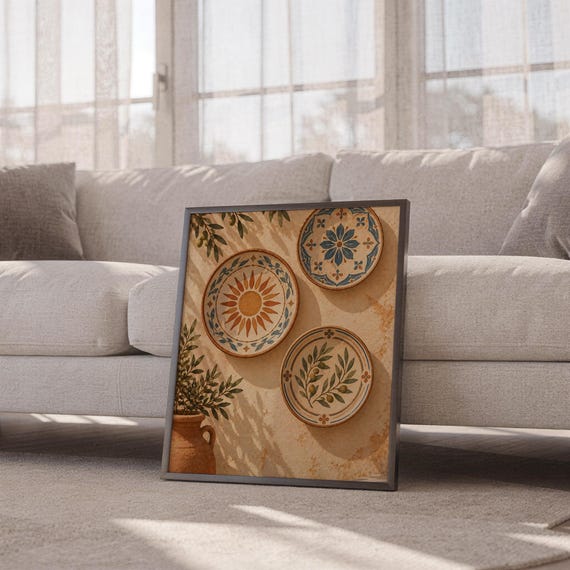 Mediterranean ceramic plate wall art print leaning against a white sofa in a bright living room with sheer curtains.