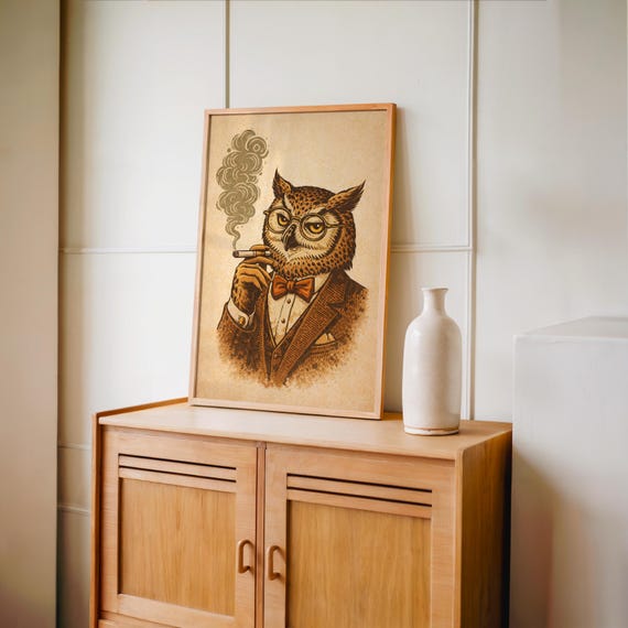 A framed print of an owl in a brown suit, red bow tie, and glasses, smoking a cigar with smoke curling up, sits on a light wood shelf with a pink salt lamp and a brown vase.