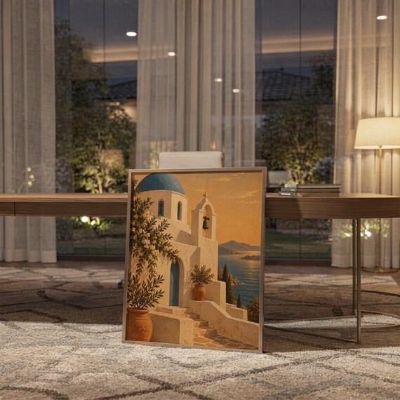 Santorini church wall art print standing on a wooden desk in a home office in warm evening light.