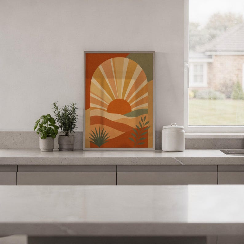 Boho sun arch print standing on a white kitchen counter beside potted herbs.