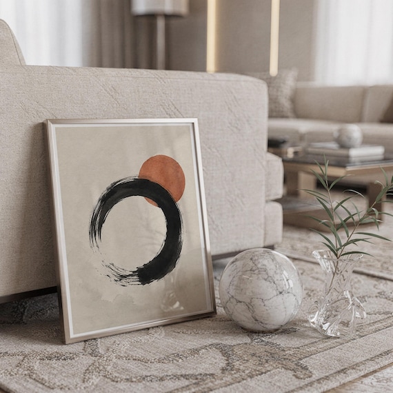Framed Japanese brushstroke art leaning on the floor next to a white marble sphere.