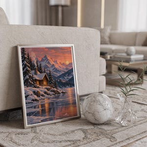 Winter cabin mountain wall art print in a silver frame leaning against a sofa beside a decorative marble sphere.