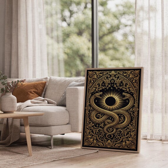 Occult snake wall art print leaning on the floor beside a cream armchair next to large garden windows.