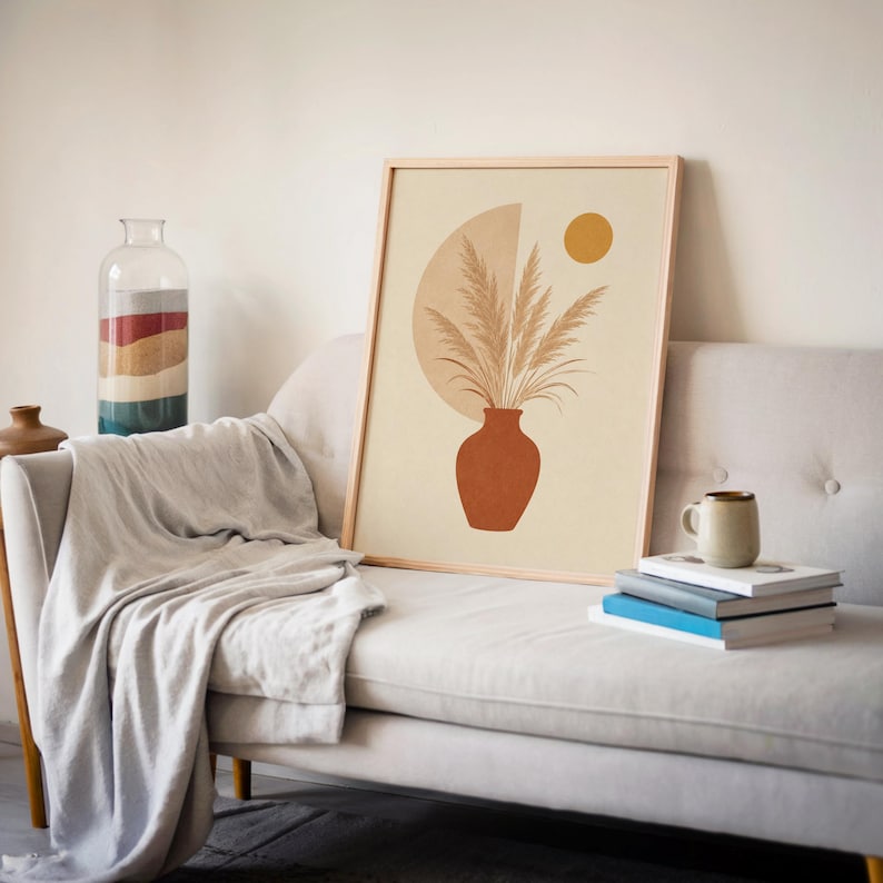 Single framed pampas grass in a terracotta vase art print displayed on a white sofa.