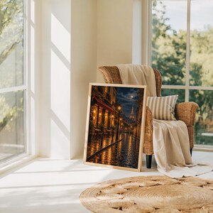 Paris eiffel tower wall art print leaning on the floor beside a rattan armchair and jute rug in a bright sunlit room.