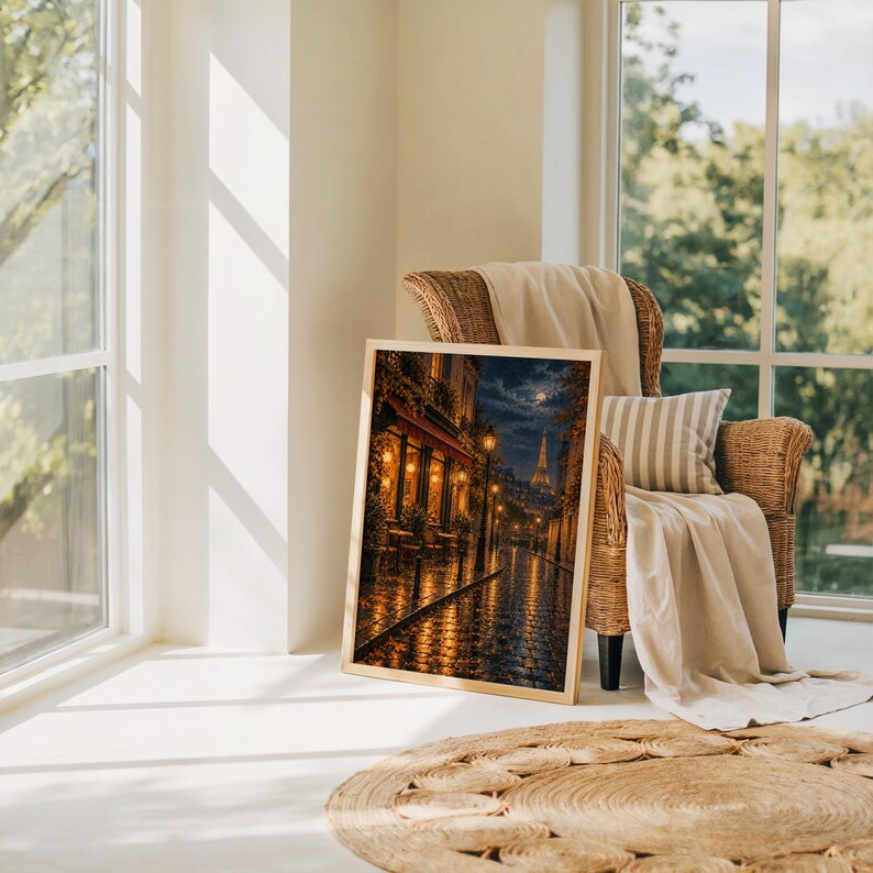 Paris eiffel tower wall art print leaning on the floor beside a rattan armchair and jute rug in a bright sunlit room.