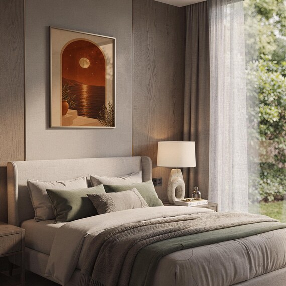 Moonlit Mediterranean arch print hanging above a bed with sage green pillows in a calm neutral bedroom.