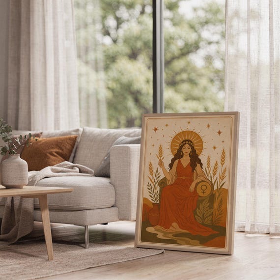 Celestial goddess wall art print leaning on the floor beside a cream armchair next to large garden windows.