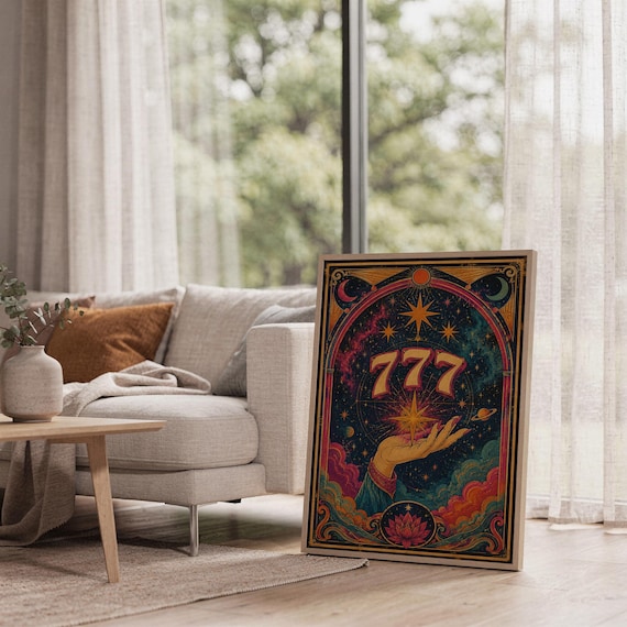 777 angel number wall art print leaning on the floor beside a cream armchair next to large garden windows.