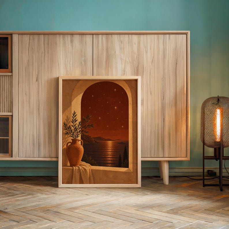 Mediterranean night sea wall art print leaning against a wooden cabinet by a teal wall beside a glowing floor lamp.
