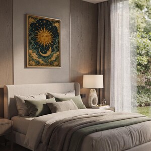 Celestial sun and moon wall art print hanging above a bed with sage green pillows in a calm neutral bedroom.