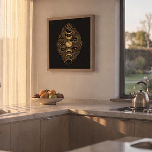 Gold snake moon phase wall art print hanging above a stone countertop with a fruit bowl in a sunny kitchen.