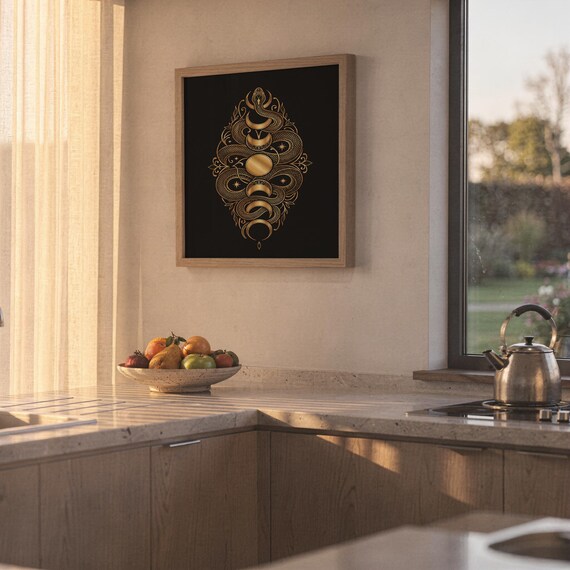 Gold snake moon phase wall art print hanging above a stone countertop with a fruit bowl in a sunny kitchen.
