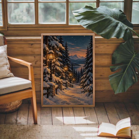 Snowy forest path wall art print leaning against warm wood paneling beside a wooden armchair and a monstera plant.