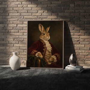Regal rabbit portrait wall art print in a white frame leaning against a gray sofa on a sunlit wooden floor.