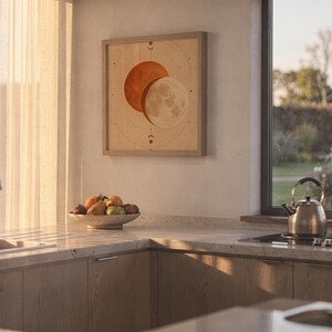 Sun and moon celestial wall art print hanging above a stone countertop with a fruit bowl in a sunny kitchen.