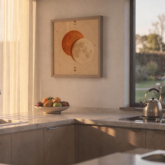 Sun and moon celestial wall art print hanging above a stone countertop with a fruit bowl in a sunny kitchen.