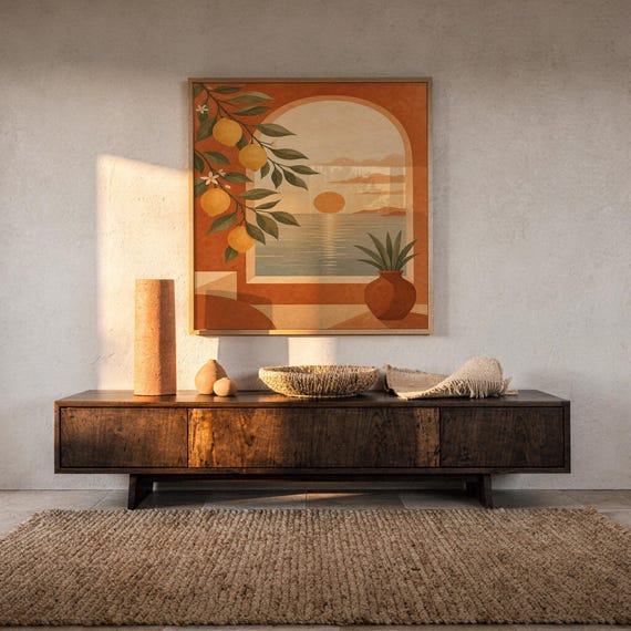 Mediterranean lemon and sea view arch print hanging above a dark wood console and jute rug in a warm neutral interior.
