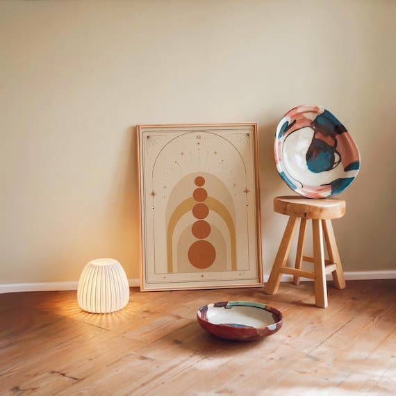 Aesthetic neutral geometric arch poster framed on wooden floor with ambient night lamp.