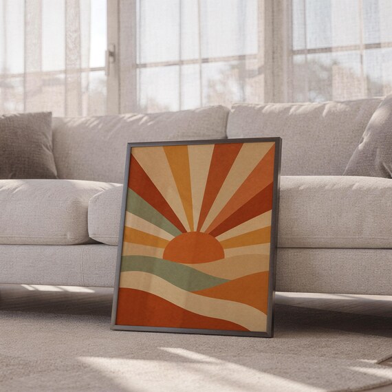 Retro geometric sunrise print leaning against a white sofa in a bright living room with sheer curtains.