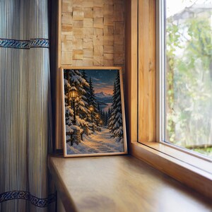 Snowy forest path wall art print standing on a wooden window sill in warm natural light.
