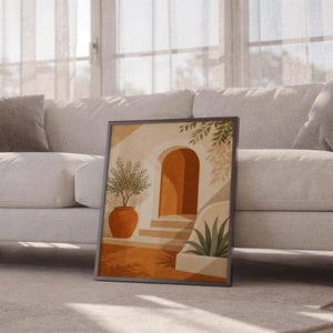 Mediterranean terracotta stairway arch print leaning against a white sofa in a bright living room with sheer curtains.