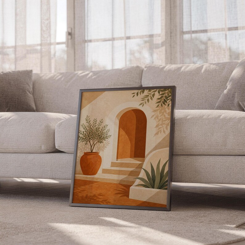 Mediterranean terracotta stairway arch print leaning against a white sofa in a bright living room with sheer curtains.