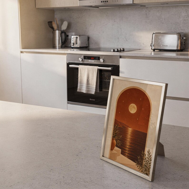 Moonlit Mediterranean arch print standing on a countertop in a modern white kitchen.