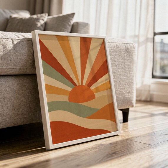 Retro geometric sunrise print in a white frame leaning against a gray sofa on a sunlit wooden floor.