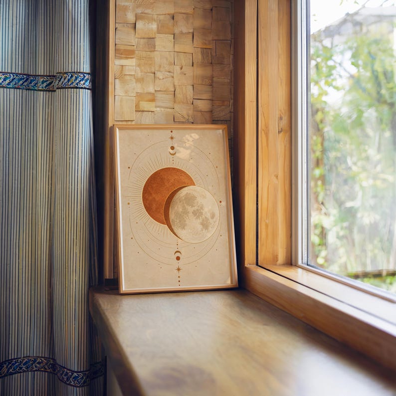 Sun and moon celestial wall art print standing on a wooden window sill in warm natural light.