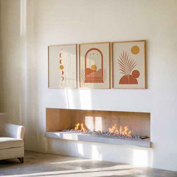 Set of 3 terracotta sun and moon phases wall art prints framed side by side above a modern indoor fireplace, creating a warm, cozy, and sophisticated living room gallery wall set focal point with soft ambient shadows.