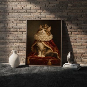 Royal cat portrait wall art print in a white frame leaning against a gray sofa on a sunlit wooden floor.