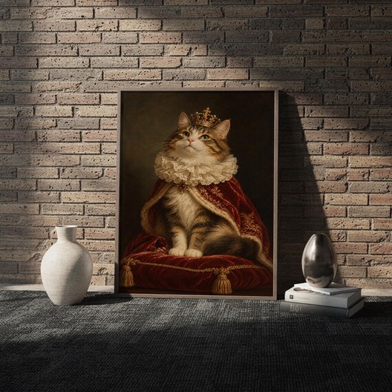 Royal cat portrait wall art print in a white frame leaning against a gray sofa on a sunlit wooden floor.