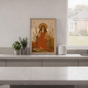 Celestial goddess wall art print standing on a white kitchen counter beside potted herbs.