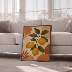 Lemon branch botanical print leaning against a white sofa in a bright living room with sheer curtains.