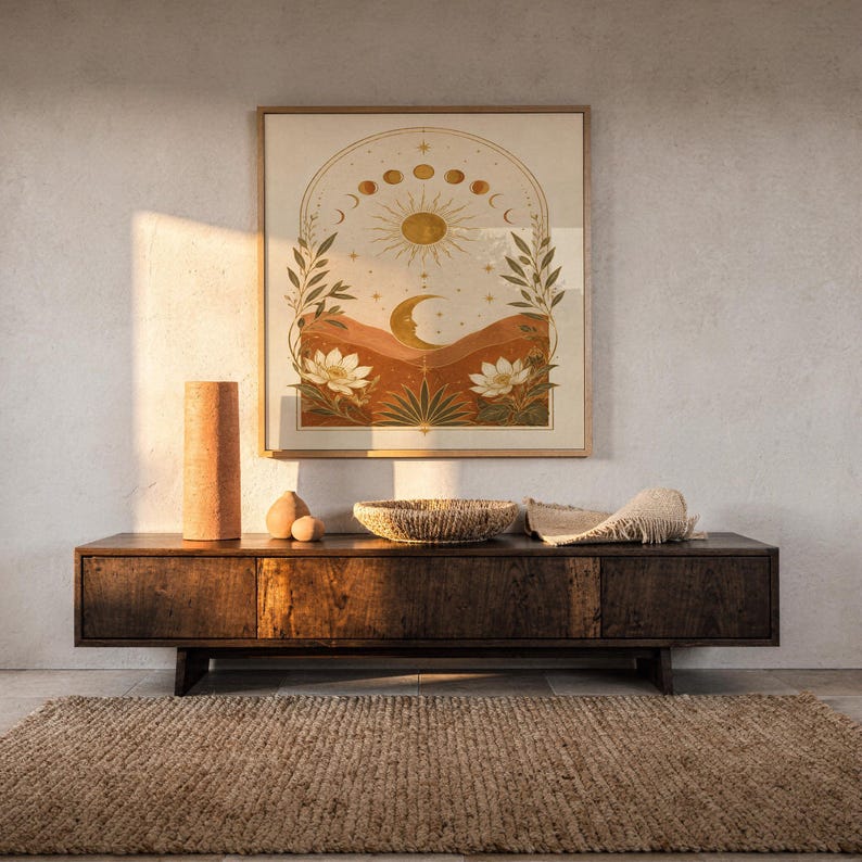 Celestial sun and moon wall art print hanging above a dark wood console and jute rug in a warm neutral interior.