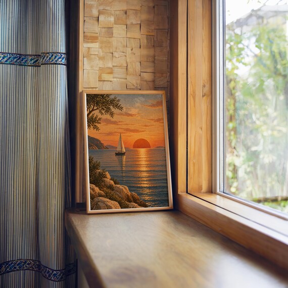 Sunset sailboat wall art print standing on a wooden window sill in warm natural light.