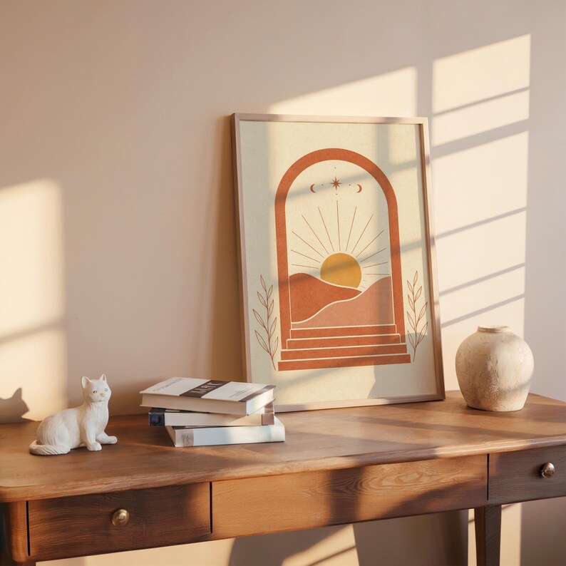 Terracotta desert poster on dark wooden desk beside stacked books and ceramic vase