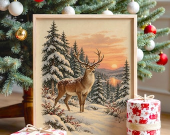 Könnte beinhalten: Ein gerahmter rechteckiger Druck mit einem Hirsch in einer verschneiten Waldlandschaft mit Tannen und einem Sonnenuntergangshimmel. Der Druck steht neben zwei quadratischen und zylindrischen Geschenkboxen mit weißem Papier.