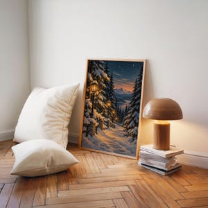 Snowy forest path wall art print leaning on a herringbone wood floor beside cream cushions and a wooden mushroom lamp.